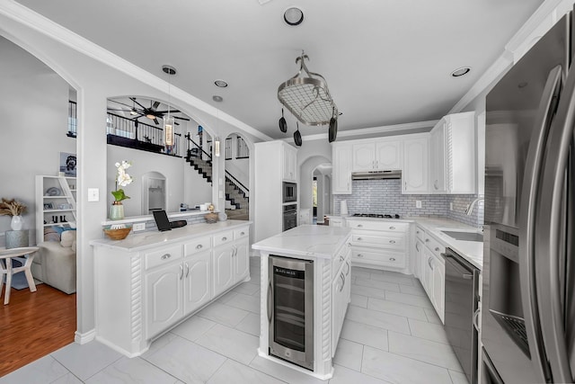 kitchen with a sink, stainless steel appliances, wine cooler, and arched walkways