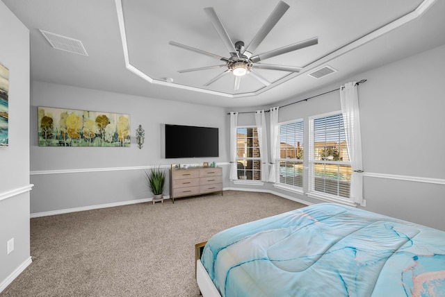 carpeted bedroom featuring visible vents, baseboards, a raised ceiling, and a ceiling fan