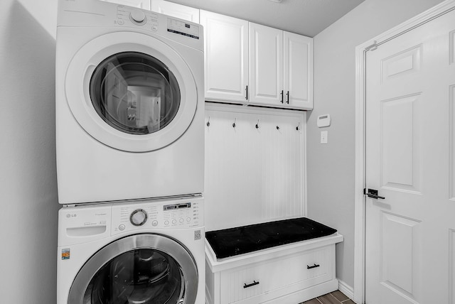 washroom with cabinet space, stacked washer and clothes dryer, and baseboards