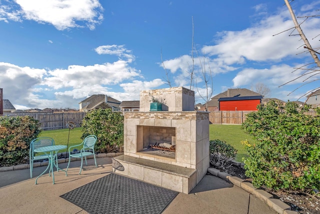 view of patio with exterior fireplace and a fenced backyard