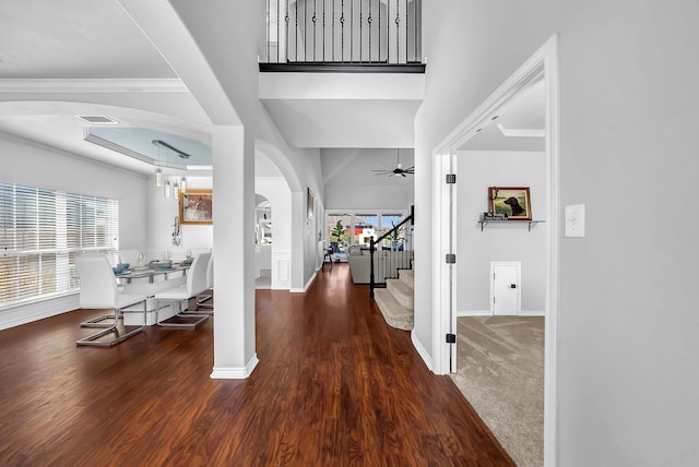 foyer featuring visible vents, stairway, a towering ceiling, wood finished floors, and arched walkways