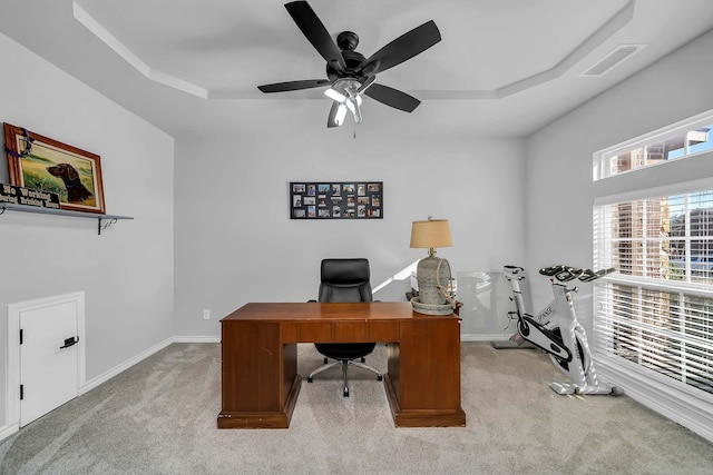 home office featuring visible vents, a raised ceiling, carpet floors, baseboards, and ceiling fan