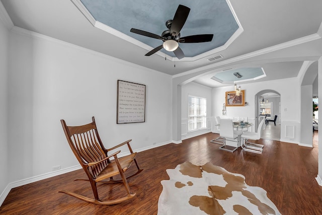 living area featuring visible vents, ornamental molding, wood finished floors, arched walkways, and a raised ceiling