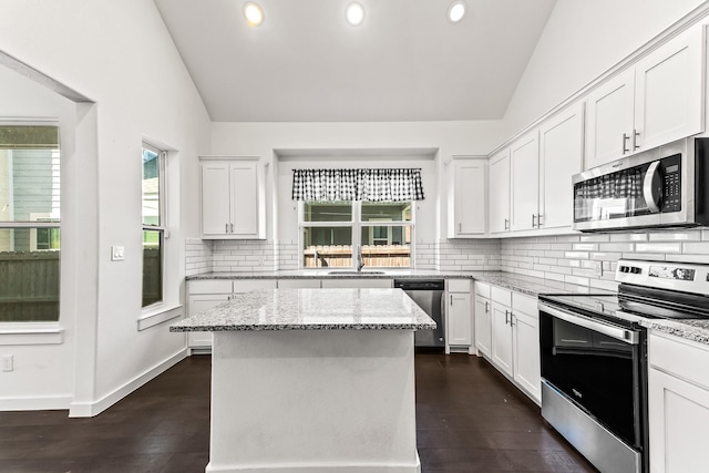 kitchen featuring white cabinetry, vaulted ceiling, appliances with stainless steel finishes, and a kitchen island