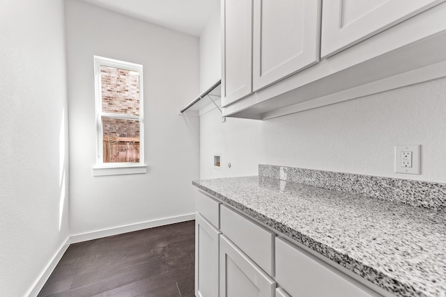 kitchen with dark wood finished floors, white cabinets, baseboards, and light stone countertops