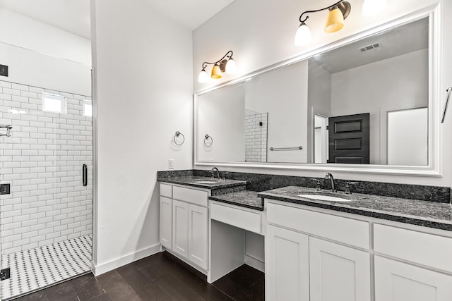 bathroom featuring a shower stall, wood finished floors, double vanity, and a sink