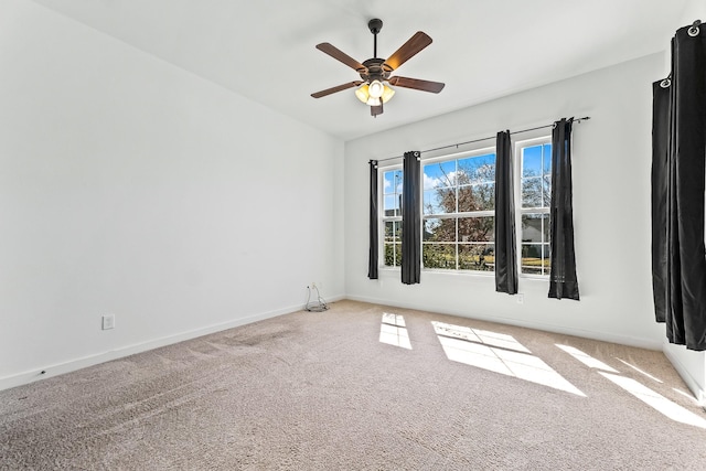 carpeted spare room featuring a ceiling fan, baseboards, and vaulted ceiling