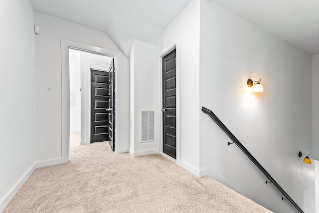 corridor with visible vents, an upstairs landing, carpet, and baseboards