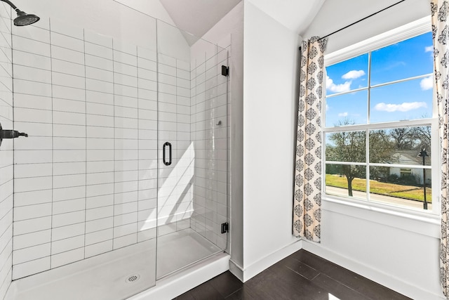 full bathroom featuring baseboards, wood finished floors, a stall shower, and vaulted ceiling