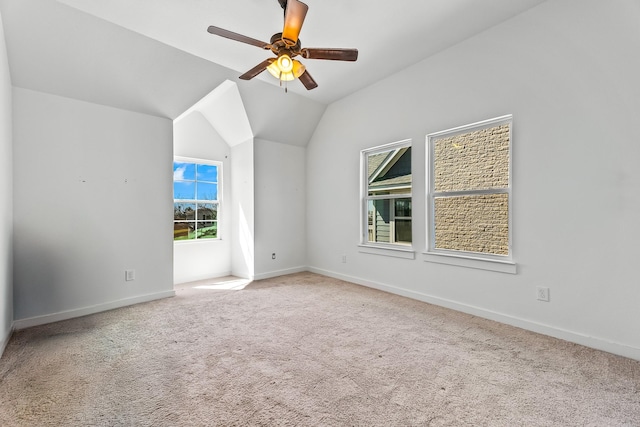 carpeted spare room with lofted ceiling, a ceiling fan, and baseboards