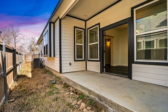 entrance to property with a patio, central AC unit, and fence