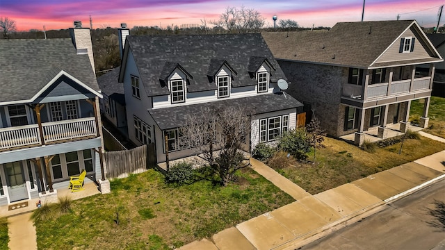 view of front of property with a shingled roof, a balcony, and a chimney