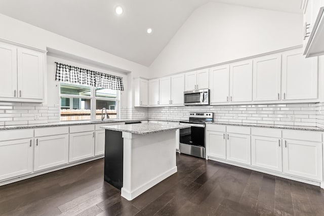 213 E 5th St, Ferris, TX 75125 - kitchen featuring stainless steel appliances, a sink, white cabinets, tasteful backsplash, and high vaulted ceiling