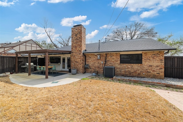 back of house with brick siding, french doors, a chimney, a fenced backyard, and a patio area