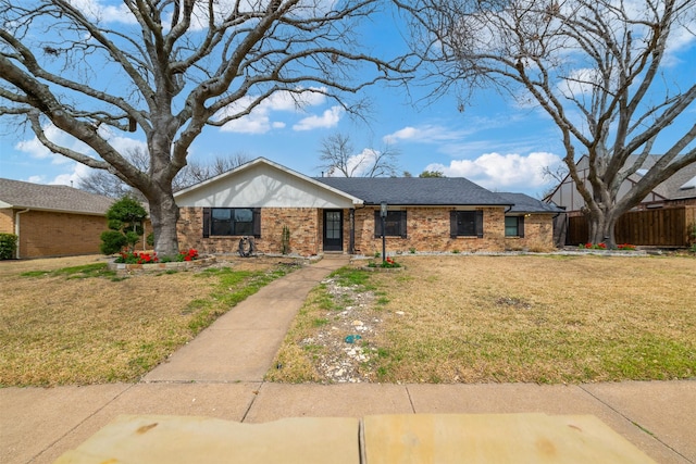 ranch-style house with brick siding, roof with shingles, a front yard, and fence