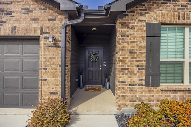 view of exterior entry featuring an attached garage and brick siding