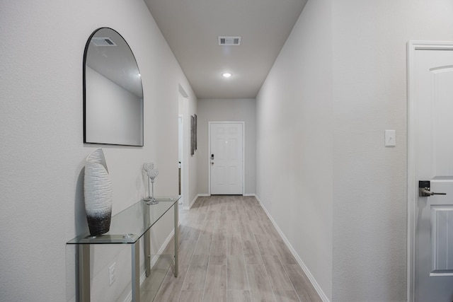 corridor with visible vents, baseboards, and light wood-style floors