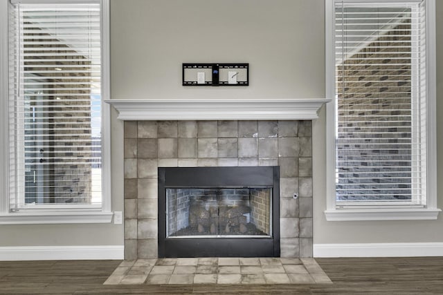 interior details with a tiled fireplace, wood finished floors, and baseboards