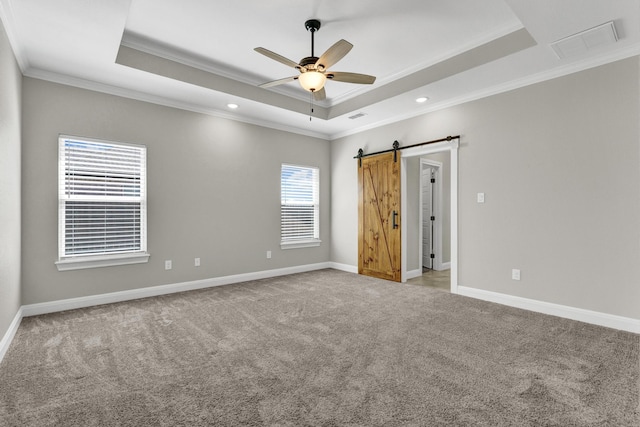 unfurnished bedroom with a barn door, a raised ceiling, carpet floors, and visible vents