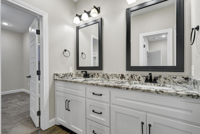 bathroom featuring double vanity, baseboards, and a sink