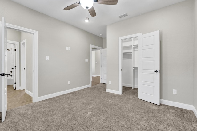 unfurnished bedroom featuring visible vents, a walk in closet, baseboards, and carpet floors