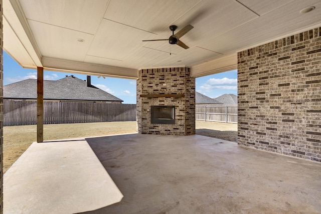 view of patio with a fenced backyard, a ceiling fan, and an outdoor brick fireplace