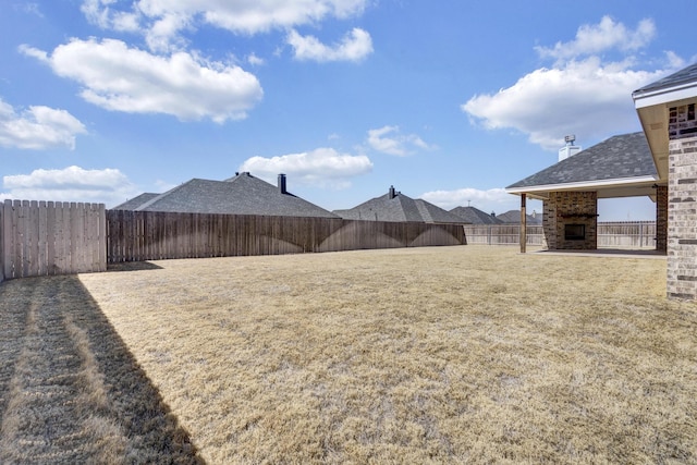 view of yard featuring a fenced backyard and a fireplace