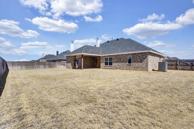 rear view of house featuring cooling unit, brick siding, a fenced backyard, and a lawn