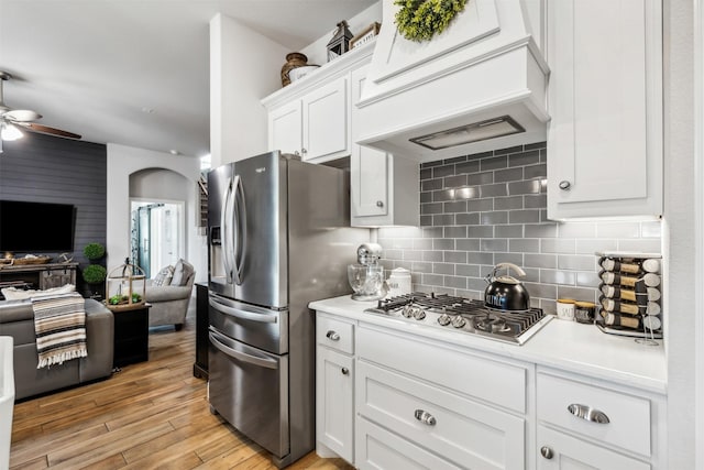 kitchen featuring premium range hood, open floor plan, light countertops, arched walkways, and stainless steel appliances