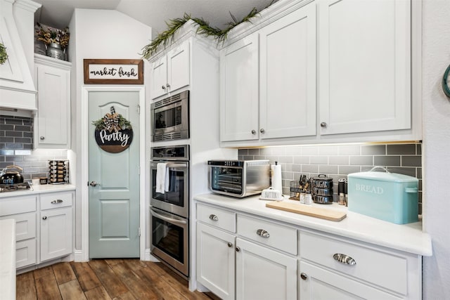 kitchen featuring backsplash, dark wood finished floors, white cabinetry, stainless steel appliances, and light countertops