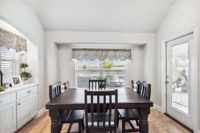 dining area with baseboards, light wood-type flooring, and lofted ceiling