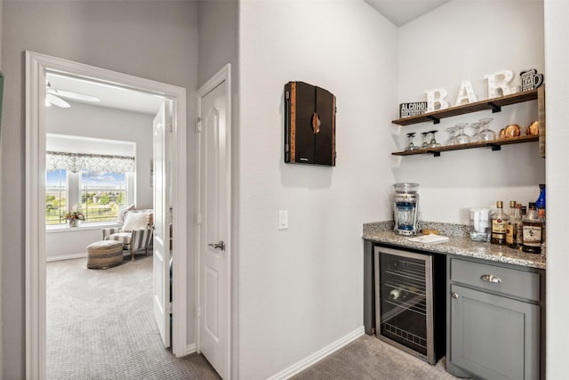 bar with a bar, wine cooler, light colored carpet, and baseboards