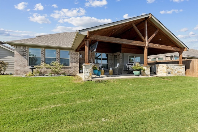 back of house with brick siding, a lawn, a shingled roof, and a patio