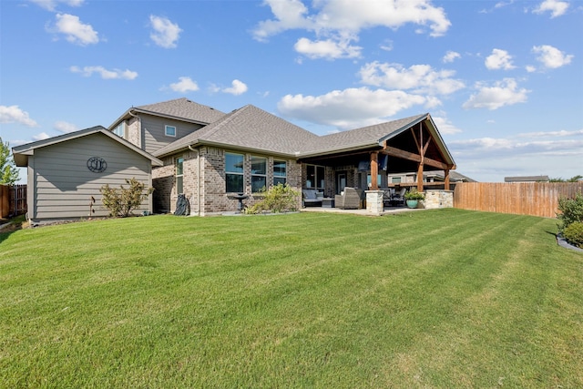 rear view of house with a patio, fence, a yard, roof with shingles, and brick siding