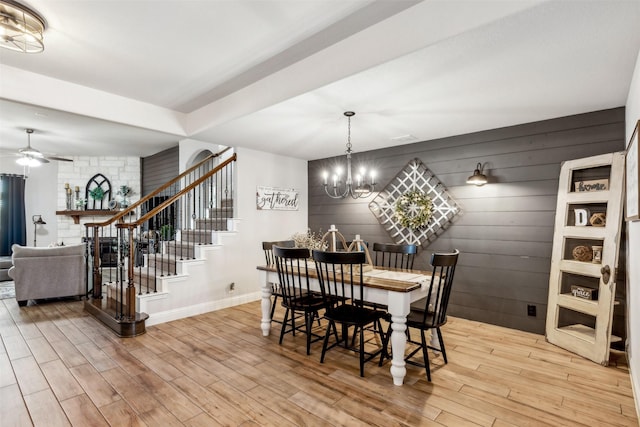 dining area with stairs, ceiling fan with notable chandelier, wood finished floors, and baseboards