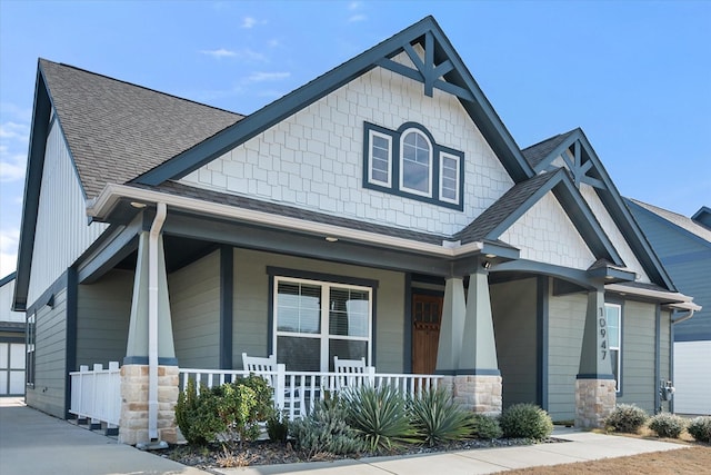 craftsman inspired home with roof with shingles and a porch