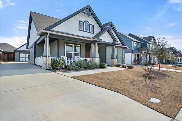 craftsman house with stone siding, covered porch, a residential view, and a garage