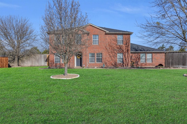 back of house with a yard, brick siding, roof with shingles, and fence