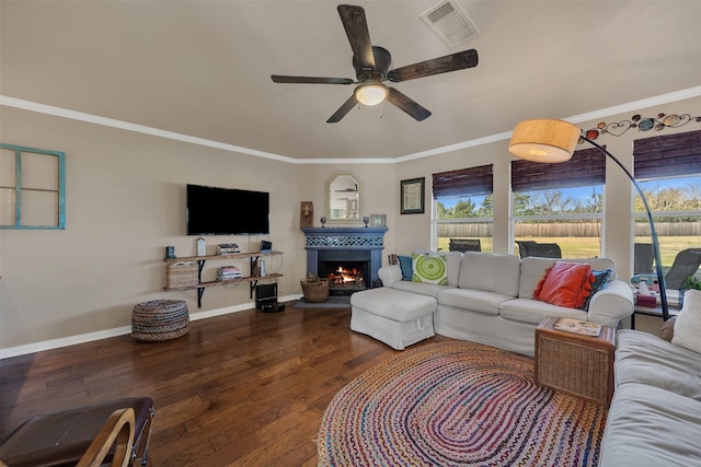 living area featuring visible vents, a warm lit fireplace, wood finished floors, and ornamental molding