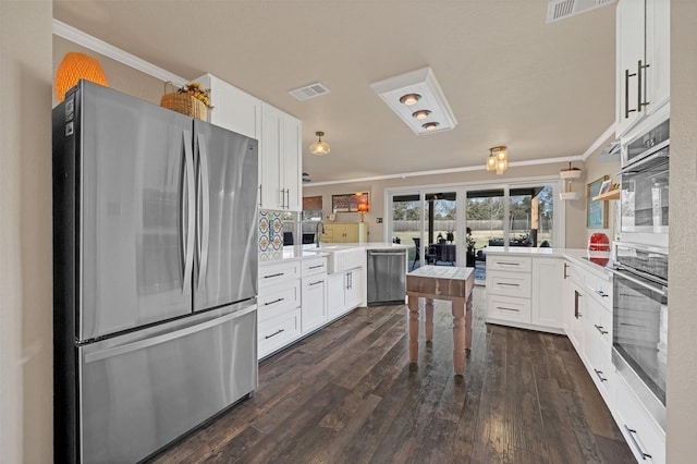 kitchen with visible vents, appliances with stainless steel finishes, a peninsula, and crown molding