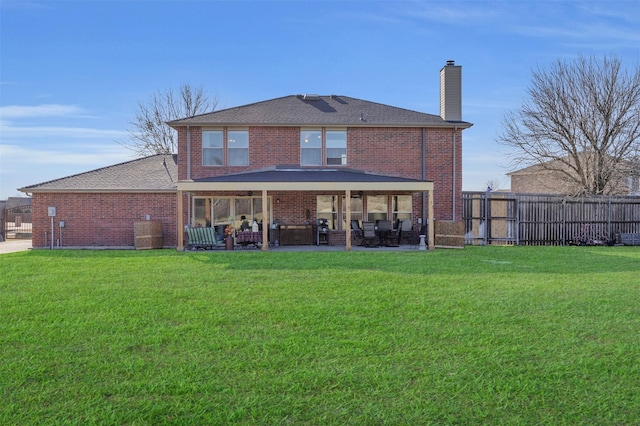 back of house with a yard, brick siding, and fence