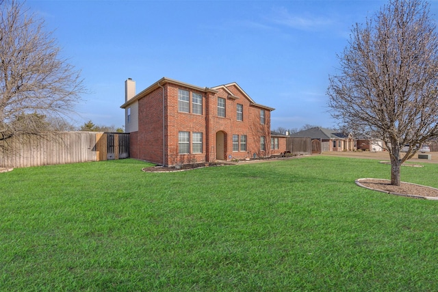 view of front facade with a front yard, brick siding, a chimney, and fence