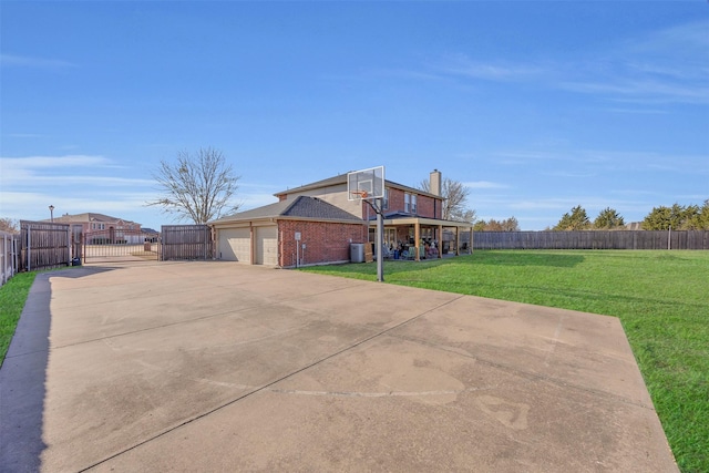 exterior space featuring brick siding, fence, a lawn, driveway, and a gate