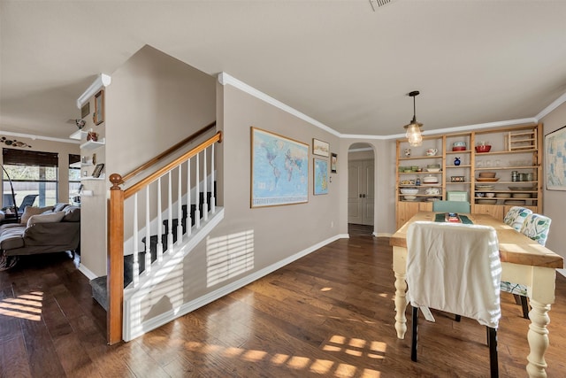 dining room featuring hardwood / wood-style floors, stairs, arched walkways, and ornamental molding