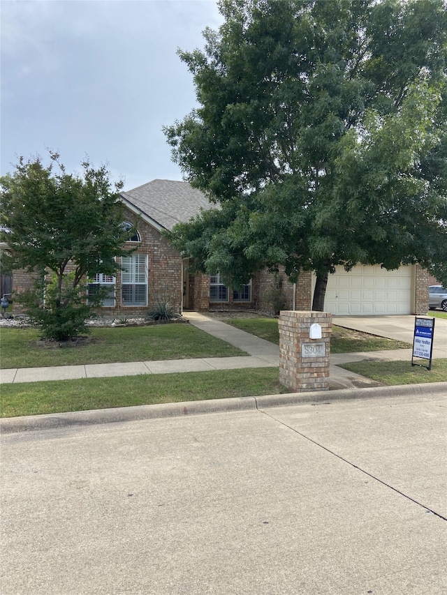 8304 Emerald Cir, North Richland Hills, TX 76180 - obstructed view of property with driveway, a garage, and brick siding
