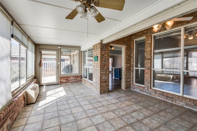 unfurnished sunroom featuring a wall mounted air conditioner and a ceiling fan