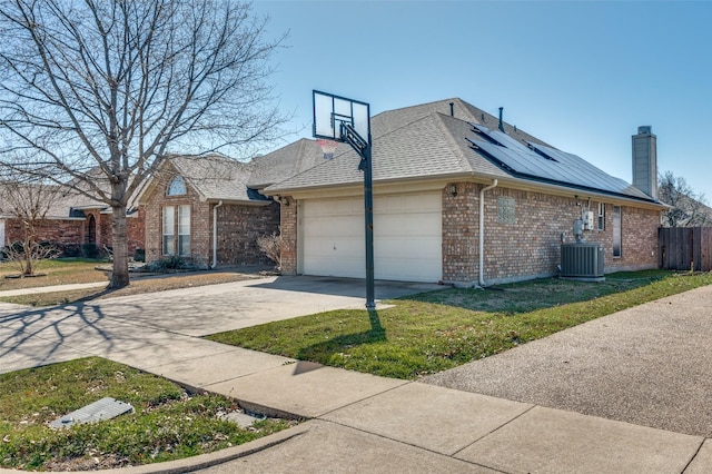 view of side of property with solar panels, an attached garage, central AC unit, and brick siding