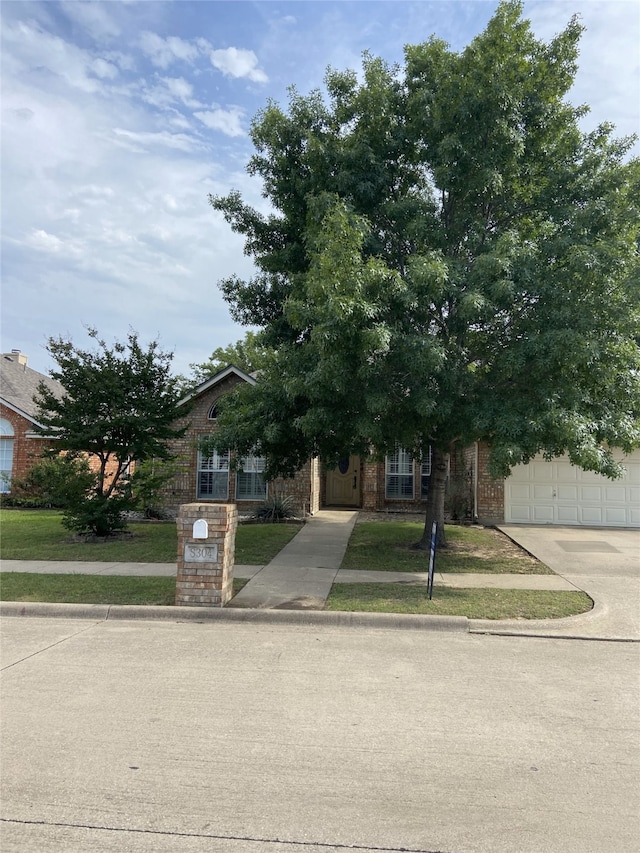 8304 Emerald Cir, North Richland Hills, TX 76180 - obstructed view of property featuring concrete driveway, a garage, brick siding, and a front lawn