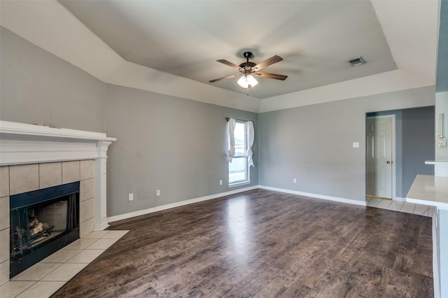 8304 Emerald Cir, North Richland Hills, TX 76180 - unfurnished living room with a tray ceiling, ceiling fan, a tile fireplace, wood finished floors, and baseboards