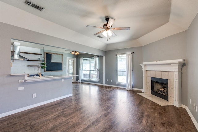 unfurnished living room with visible vents, wood finished floors, a fireplace, baseboards, and ceiling fan